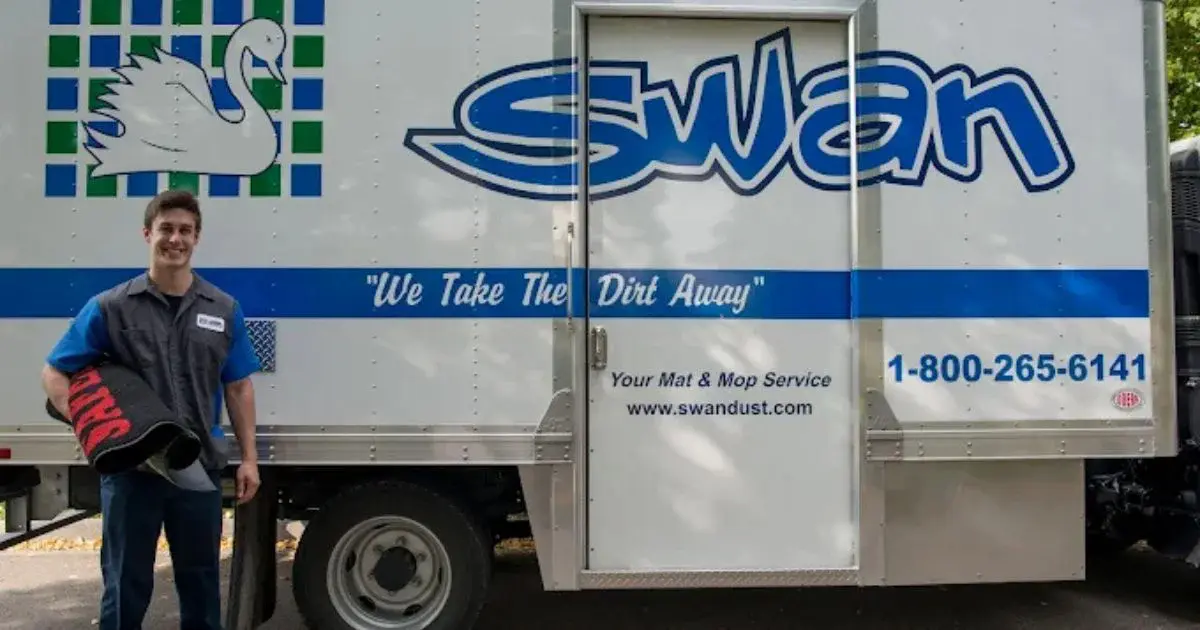 Swan Dust Control worker holding mats by company truck